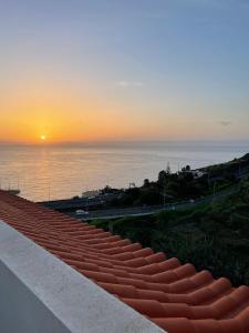 una vista de la puesta de sol sobre el océano en Penthouse Palmeira, en Gaula