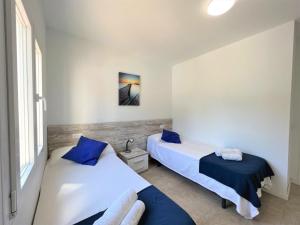 Duas camas num pequeno quarto com almofadas azuis em Trèvol I em Cielo de Bonaire 
