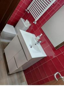 baño con lavabo blanco y suelo de baldosa roja en corazón San Bartolomé, en Madrid
