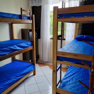 a room with three bunk beds and a window at Apartamento Pé na Areia in Caraguatatuba