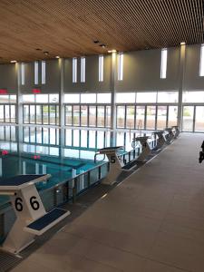 une rangée de tables dans un bâtiment avec piscine dans l'établissement Hote du Lion, à Saint-Genis-Pouilly