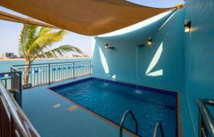 a swimming pool with a blue wall and the ocean at Indium Villas Durrat Al Arus for families only in Durat  Alarous