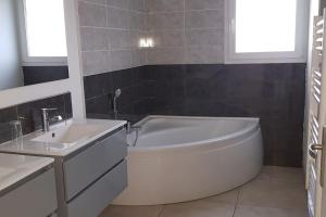een badkamer met een wit bad en een wastafel bij maison entière 8 couchages in Assieu