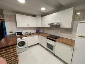 a kitchen with white cabinets and a washer and dryer at Compuerta Otañes in Otañes