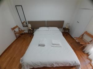 a bedroom with a white bed with two towels on it at Central Mark-Δωμάτια Διαμερίσματος in Volos