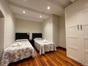 two beds in a room with white walls and wooden floors at Compuerta Otañes in Otañes
