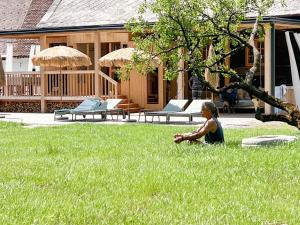 a woman sitting in the grass in front of a house at Chalet 1888 in Bad Sankt Leonhard im Lavanttal