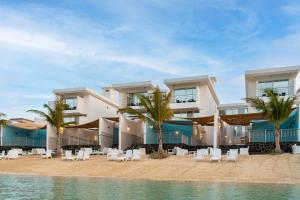 杜拉艾列拉巴斯的住宿－Indium Villas Durrat Al Arus for families only，海滩上的度假村,设有椅子和棕榈树