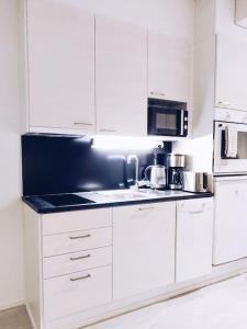 uma cozinha com armários brancos e um balcão preto em New Studio Cherry near Helsinki airport in Kivistö em Vantaa