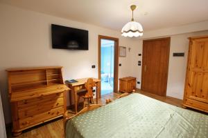 a bedroom with a bed and a desk and a table at Hotel Des Alpes in Cortina dʼAmpezzo