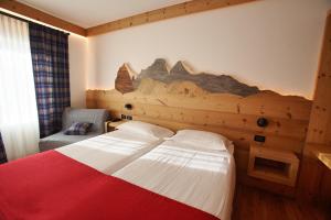a hotel room with a bed and a wall mural at Hotel Des Alpes in Cortina dʼAmpezzo
