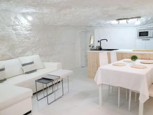 sala de estar blanca con 2 mesas y cocina en Casa Cueva a 15 minutos del centro de Valencia en Paterna