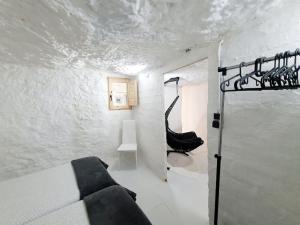 um quarto branco com uma cama e uma cadeira preta em Casa Cueva a 15 minutos del centro de Valencia em Paterna