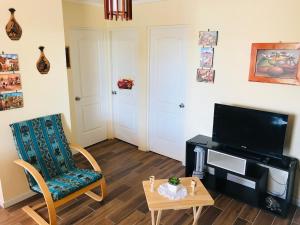 ein Wohnzimmer mit einem TV, einem Stuhl und einem Tisch in der Unterkunft Casa con Piscina privada en Pica in Iquique