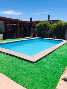 a large blue swimming pool with green grass at Casa con Piscina privada en Pica in Iquique