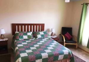a bedroom with a bed with a green and white quilt at Casa con Piscina privada en Pica in Iquique