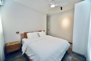 1 dormitorio con 1 cama blanca grande y mesita de noche en 10 min from Hilton Beach with free parking en Ramat Gan