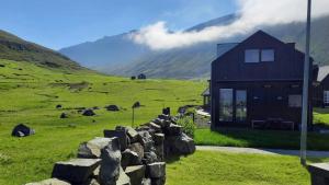 a house in a field with a rock wall at Luxury Cottage with Stunning Views - Okkara summarhús við Gjógv in Við Gjógv