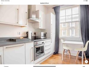 a kitchen with white cabinets and a table and a window at Central London Warwick Sq, in London