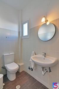 a bathroom with a toilet and a sink and a mirror at Soultana Rooms & Studios in Pollonia