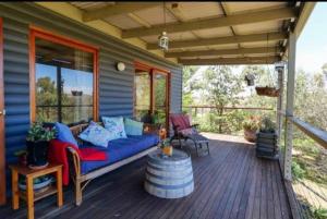 CaperteeBlack Wattle Cabin Turon Escape Capertee的木甲板上设有1个带蓝色沙发的门廊