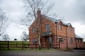 a large wooden house with a fence around it at Millmoor Farm Holidays in Malpas