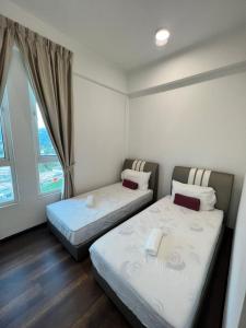 twee bedden in een kamer met een raam bij Spacious Family Staycation 3BR at Ipoh Uptown in Ipoh