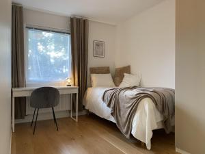a bedroom with a bed and a desk and a window at Luxurious villa with free parking in Gothenburg