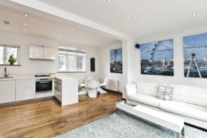 a living room with a white couch and a kitchen at Designer 2 bedroom Pimlico in London