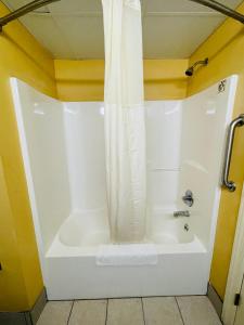 e bagno con vasca bianca e tenda doccia. di Mountain inn & suites - Dunlap TN a Dunlap