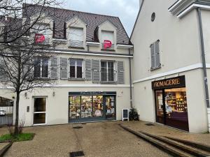 ein Geschäft vor einem weißen Gebäude in der Unterkunft Duplex les Oiseaux du Verger, au coeur de la ville in Verneuil-sur-Seine