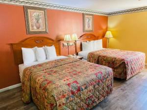 two beds in a hotel room with orange walls at Mountain inn & suites - Dunlap TN in Dunlap