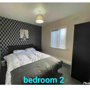 1 dormitorio con 1 cama con pared estampada en blanco y negro en Cheerful 3 bed semi-detached property, en Bradford