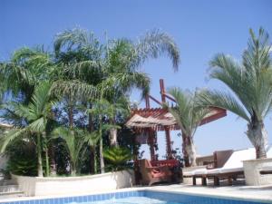 a swimming pool with palm trees next to a resort at Sun Set Suite Villa in Peyia