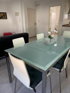 - une table en verre avec des chaises blanches dans l'établissement Lujoso y amplio apartamento en Crevillente, à Crevillente