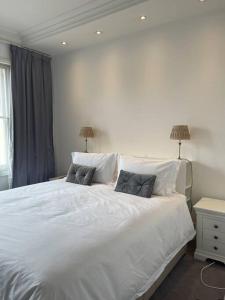 una camera da letto con un grande letto bianco con due cuscini di Stunning Grand 2 bed, 2 bath apartment, a Londra
