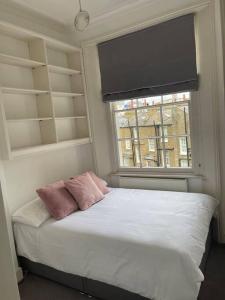 a bed with two pillows in a room with a window at Stunning Grand 2 bed, 2 bath apartment, in London