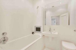 a white bathroom with a sink and a tub and a toilet at Stunning Grand 2 bed, 2 bath apartment, in London