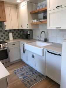 a kitchen with white cabinets and a sink at Newly Renovated Creekside Cabin! in Almont