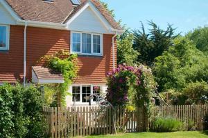 uma cerca de madeira em frente a uma casa com flores em Canal view 2 bed end of terrace em Chichester