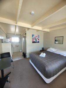 a bedroom with a large bed and a kitchen at Railway Hotel/Motel Hokitika in Hokitika