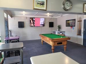 a room with a pool table and a clock on the wall at Railway Hotel/Motel Hokitika in Hokitika