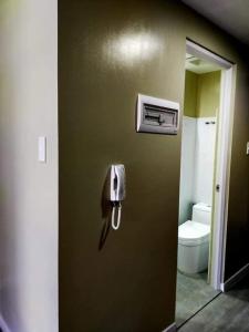 a phone on a wall in a bathroom with a toilet at Nahas Condo Hotel in Manila