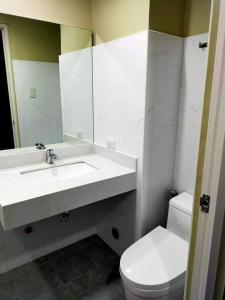 a bathroom with a sink and a toilet and a mirror at Nahas Condo Hotel in Manila