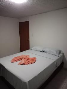 Una cama blanca con una toalla naranja. en Alex home west cali, en Cali