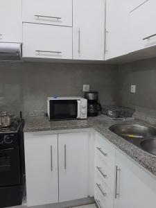 a kitchen with white cabinets and a microwave on a counter at Núria's Apartment in Mindelo
