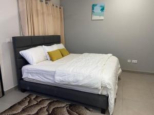 a bedroom with a bed with white sheets and yellow pillows at Queens View Apartment in Accra