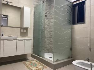 a bathroom with a shower with a toilet and a sink at Queens View Apartment in Accra
