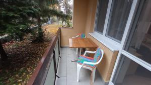 einen Balkon mit einem Holztisch und 2 Stühlen in der Unterkunft Londira Apartman Hévíz in Hévíz