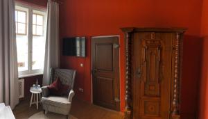 EllingenにあるGasthof Römischer Kaiserの赤い壁のベッドルーム1室、ドア1つ、椅子1脚が備わります。